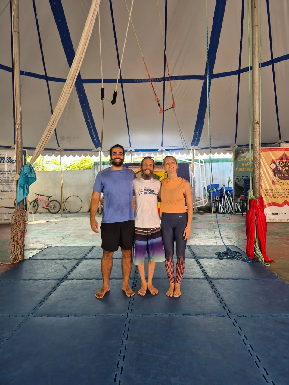 Lucas com duas pessoas durante uma aula de circo